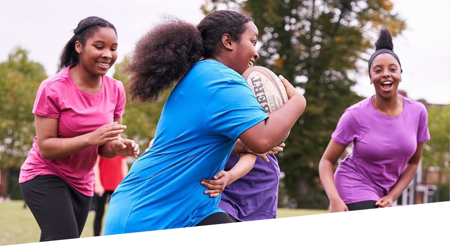Group of teenage girls having fun playing rugby outdoors