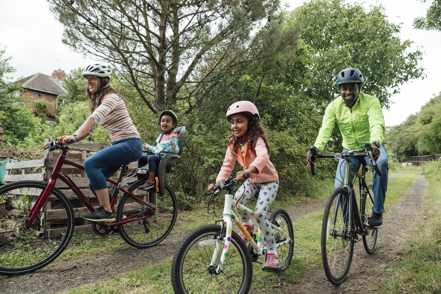 A family of four take a bike ride through a park